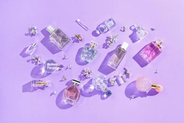 Düz kompozisyon, parfüm şişeleri ve mor arka planda leylak çiçekleri vardı.