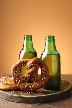 Lezzetli krakerler ve bira şişeleri ahşap masa üzerinde bej renkli gradyan arka plan, yakın çekim