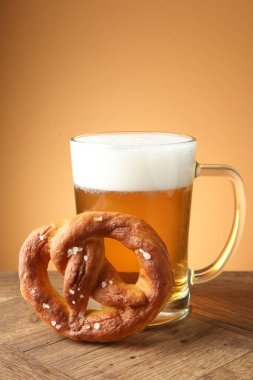 Lezzetli kraker ve cam bardak bira ahşap masada bej renkli arka planda, yakın plan