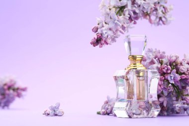 Parfüm şişesi ve mor arkaplanda leylak çiçekleri, yakın plan. Metin için boşluk