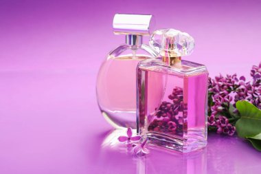 Parfümlü şişeler ve ayna yüzeyindeki leylak çiçekleri renk değişimine karşı, yakın plan. Metin için boşluk