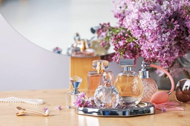 Parfüm şişeleri, aksesuarlar ve ahşap masada leylak çiçekleri.