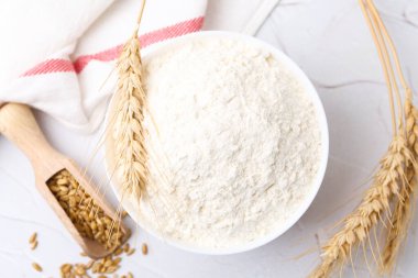 Buğday unu kasede, tahıllar ve çiviler beyaz masada, düz yerde.