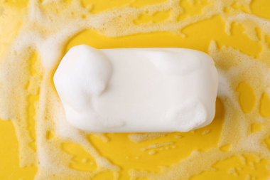 Sarı zemin üzerinde köpük olan sabun çubuğu, üst görünüm