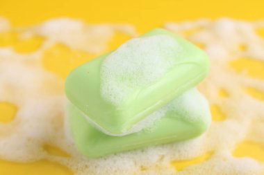 Sarı arka planda köpüklü sabun çubukları, yakın plan.