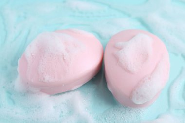 Açık mavi arka planda köpüklü sabun çubukları, yakın plan