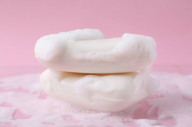 Pembe arka planda köpüklü sabun çubukları, yakın plan.