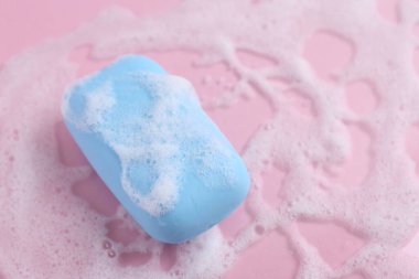 Pembe arka planda köpüklü sabun barı, üst tarafta. Metin için boşluk