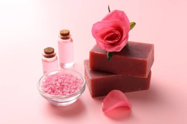 Sabun barları, kozmetik ürünleri ve pembe arka planda güzel bir gül. Yakın plan.