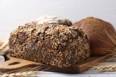 Taze ekmek somunları ve çiviler beyaz ahşap masada, yakın plan.