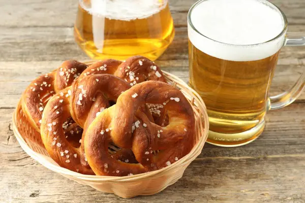 Sepette lezzetli krakerler ve ahşap masada bir bardak bira, yakın plan.