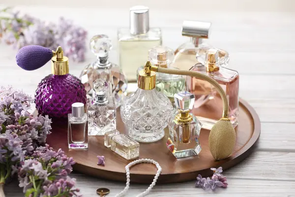 Beyaz ahşap masada parfüm, aksesuar ve leylak çiçekleri.