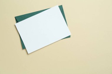 Bej arka planda boş davetiye ve zarf, üst manzara. Tasarım için boşluk