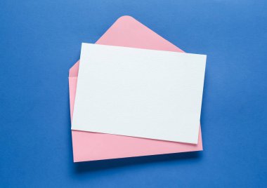 Mavi arka planda boş davetiye ve zarf, üst manzara. Tasarım için boşluk