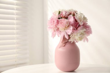 Beyaz masadaki vazoda duran bir buket güzel şakayık. Metin için boşluk