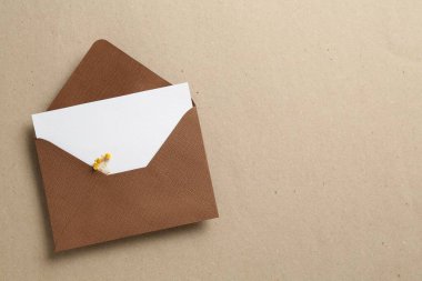 Üzerinde çiçekler ve zarf olan boş bir davetiye kartı, üst manzara. Metin için boşluk