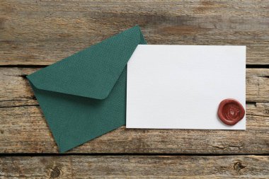 Boş davetiye kartı ve zarf ahşap masanın üstünde, üst tarafta. Tasarım için boşluk
