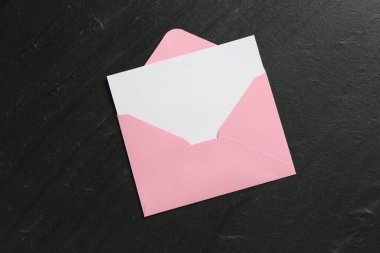 Boş davetiye kartı ve zarf siyah masanın üstünde, en üstte. Tasarım için boşluk