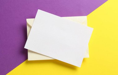 Renk arkaplan üzerinde boş davetiye ve zarf, üst görünüm. Tasarım için boşluk