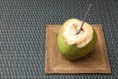 Yeşil hindistan cevizi, taze içecek ve hasır masa üzerinde saman. Metin için boşluk