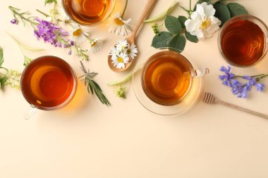 Cam fincanlarda aromatik bitki çayı ve bej arka planda farklı çiçekler, düz yatak. Metin için boşluk