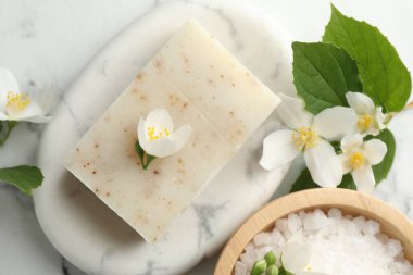 Sabun çubuğu, deniz tuzu ve yasemin çiçekleri beyaz mermer masada, düz yatıyordu.