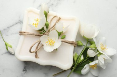 Sabun çubuğu ve yasemin çiçekleri beyaz mermer masada, düz yatıyordu.