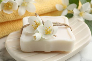 Sabun çubuğu ve yasemin çiçekleri beyaz mermer masada, yakın plan.