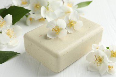 Sabun barı ve yasemin çiçekleri beyaz ahşap masada, yakın plan.