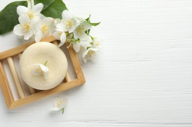 Sabun çubuğu ve yasemin çiçekleri beyaz ahşap masada, düz yerde. Metin için boşluk