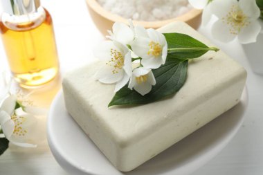 Sabun barı, deniz tuzu, temel yağ ve yasemin çiçekleri beyaz ahşap masada, yakın plan.