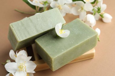 Açık kahverengi arka planda sabun ve yasemin çiçekleri, yakın plan.