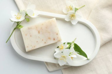 Sabun çubuğu ve yasemin çiçekleri beyaz masada, düz yatıyordu.