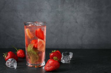 Çilekli içecek ve koyu dokulu masa üzerindeki buz gri arka planda, yakın plan. Metin için boşluk