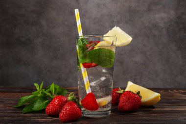 Çilek, limon ve nane ile canlandırıcı içecek ahşap masa üzerinde gri desenli arka plan, yakın plan