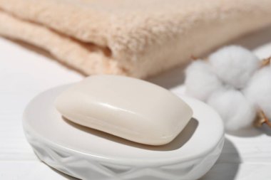 Sabun çubuğu, pamuk çiçeği ve havlu beyaz masada, yakın plan.