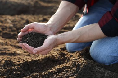 Tarlada toprak yığını tutan adam, yakın plan.