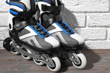 Beyaz tuğla duvarın yanındaki ahşap masada patenler, yakın plan.