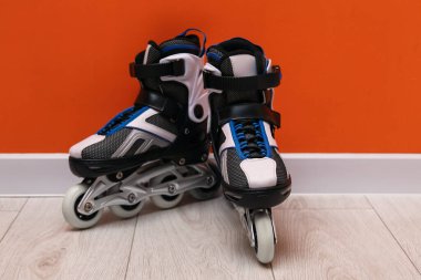 Turuncu duvarın yanında yerde bir çift paten var.