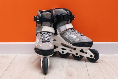 Turuncu duvarın yanında yerde bir çift paten var.