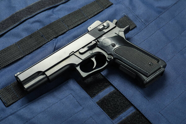 Black gun on bulletproof vest, above view. Police equipment