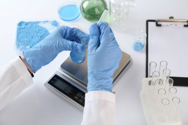 Beyaz masada numune ve ölçeklerle çalışan bilim adamı, yakın plan.