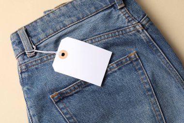 Bej arka planda etiketli mavi kot pantolon, üst görünüm