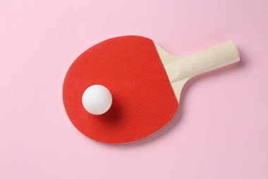 Pembe arka planda pinpon raketi ve top, üst manzara.