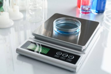 Beyaz ayna masasındaki Petri kabı ve diğer laboratuvar camlarıyla ölçeklendir, yakın plan.