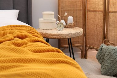 Çalar saati olan yan masa ve yatağın yanındaki dekor.