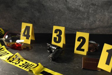 Adli tıp uzmanı. Sarı olay yeri bandı, siyah masada işaretler ve kanıtlar, yakın plan.