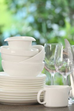 Ahşap masadaki farklı temiz tabaklar, bulanık yeşil arka plan, yakın plan