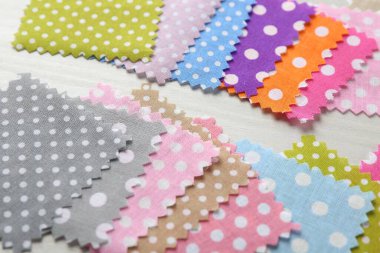 Beyaz ahşap masadaki farklı kumaşlardan örnekler, yakın plan.