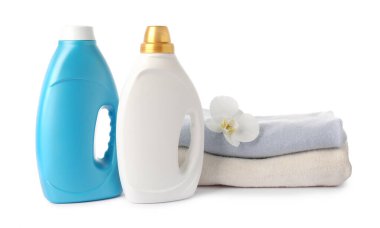 Kumaş yumuşatıcısı şişeleri, üst üste yığılmış giysiler ve beyaz üzerine izole edilmiş çiçekler.